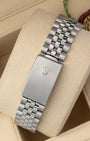 A rear view of the stainless steel Jubilee metal link watch band focusing on the secure closure of the classic stamped fold-over deployant clasp detailed with the Rolex crown emblem