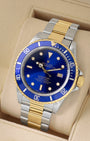 angled view of vintage 1986 Rolex Submariner 16803 featuring a blue dial, gold bezel insert, and two-tone Oyster bracelet