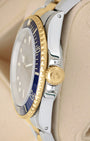 Side view close-up of the 18k yellow gold Triplock crown and blue bezel insert on a 1986 Rolex Submariner Date 16803