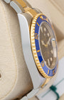 Left side profile view of the polished stainless steel case and 18k yellow gold blue ceramic bezel edge on a preowned 2018 Rolex Submariner 116613LB
