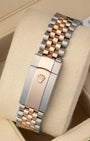 A rear view of the five-piece metal link watch band focusing on the secure closure of the two-tone folding Oysterclasp deployant buckle detailed with an embossed Rolex crown logo