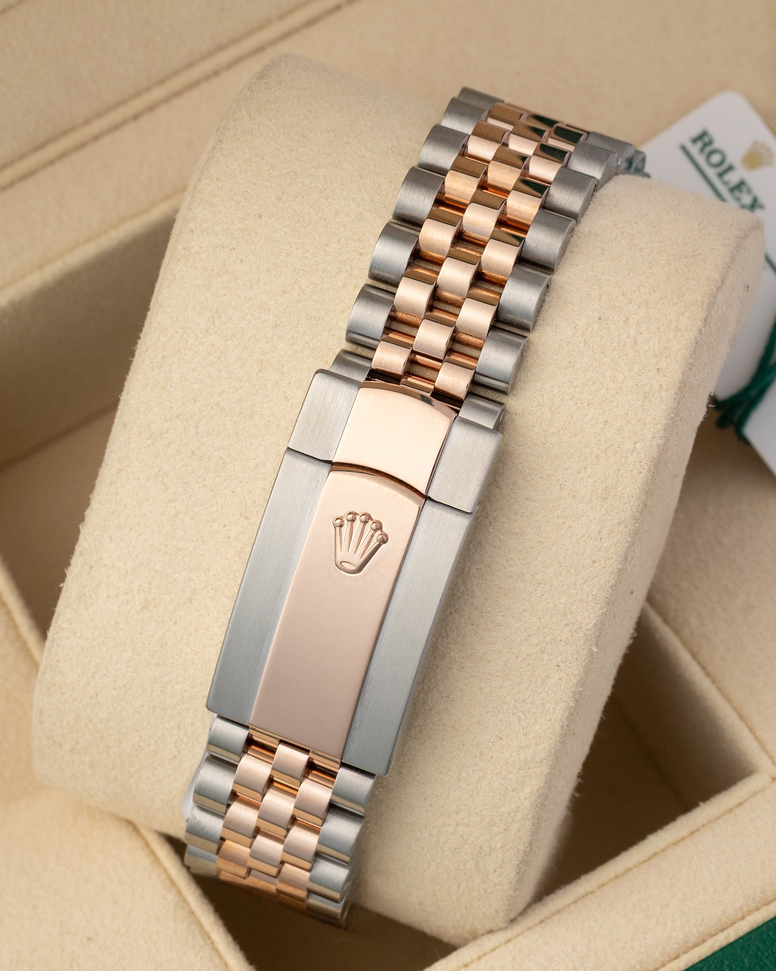 A rear view of the five-piece metal link watch band focusing on the secure closure of the two-tone folding Oysterclasp deployant buckle detailed with an embossed Rolex crown logo