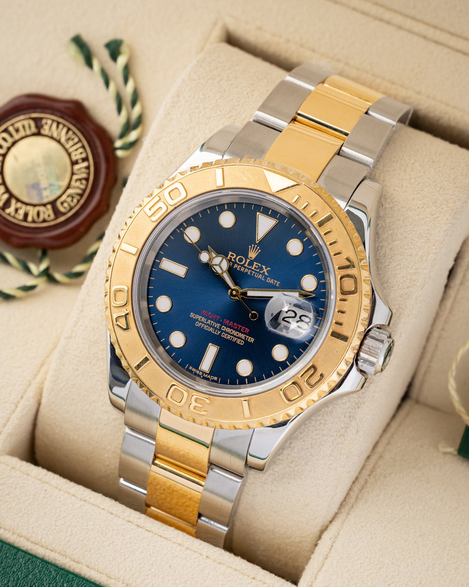 angled top-down overview of the 40mm yellow gold and steel Rolex Yacht-Master watch with a blue dial resting on its tan leather cushion