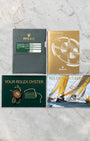 top-down flat-lay view of the green Rolex warranty card, Yacht-Master instruction manual, and official collateral paperwork on marble