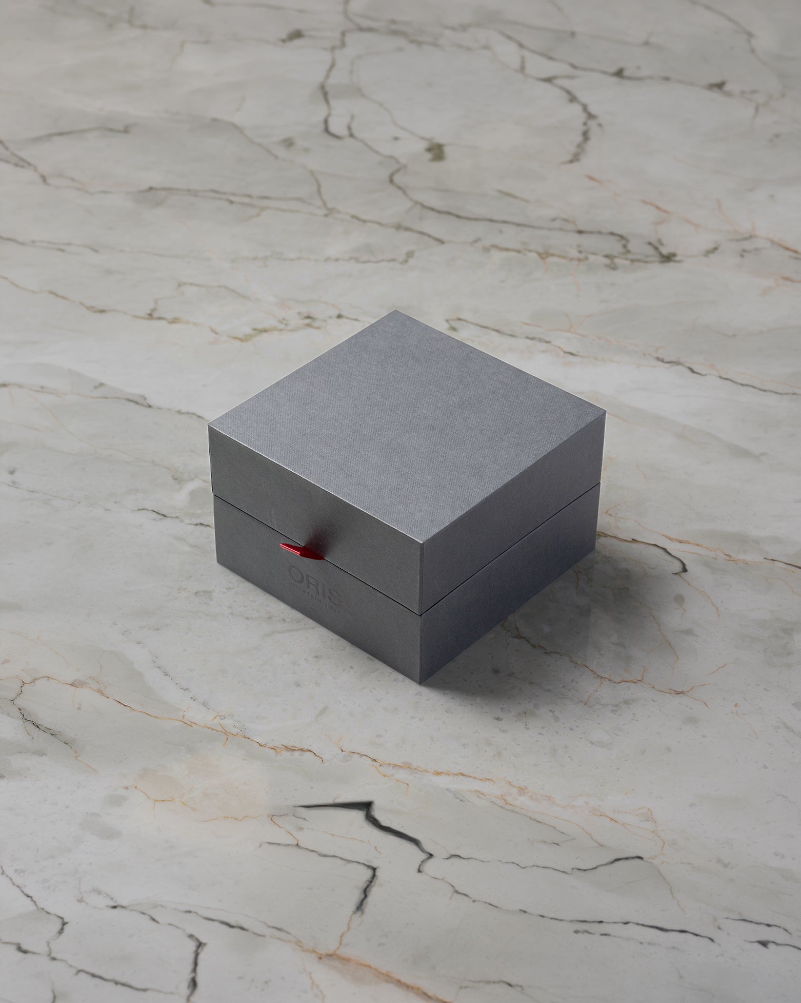 Official square grey minimalist Oris luxury watch presentation box styled with clean red security pull tab accents