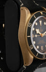 Left side perspective view highlighting the thick domed sapphire crystal, unidirectional matte slate grey aluminum bezel insert, and satin-brushed case lugs