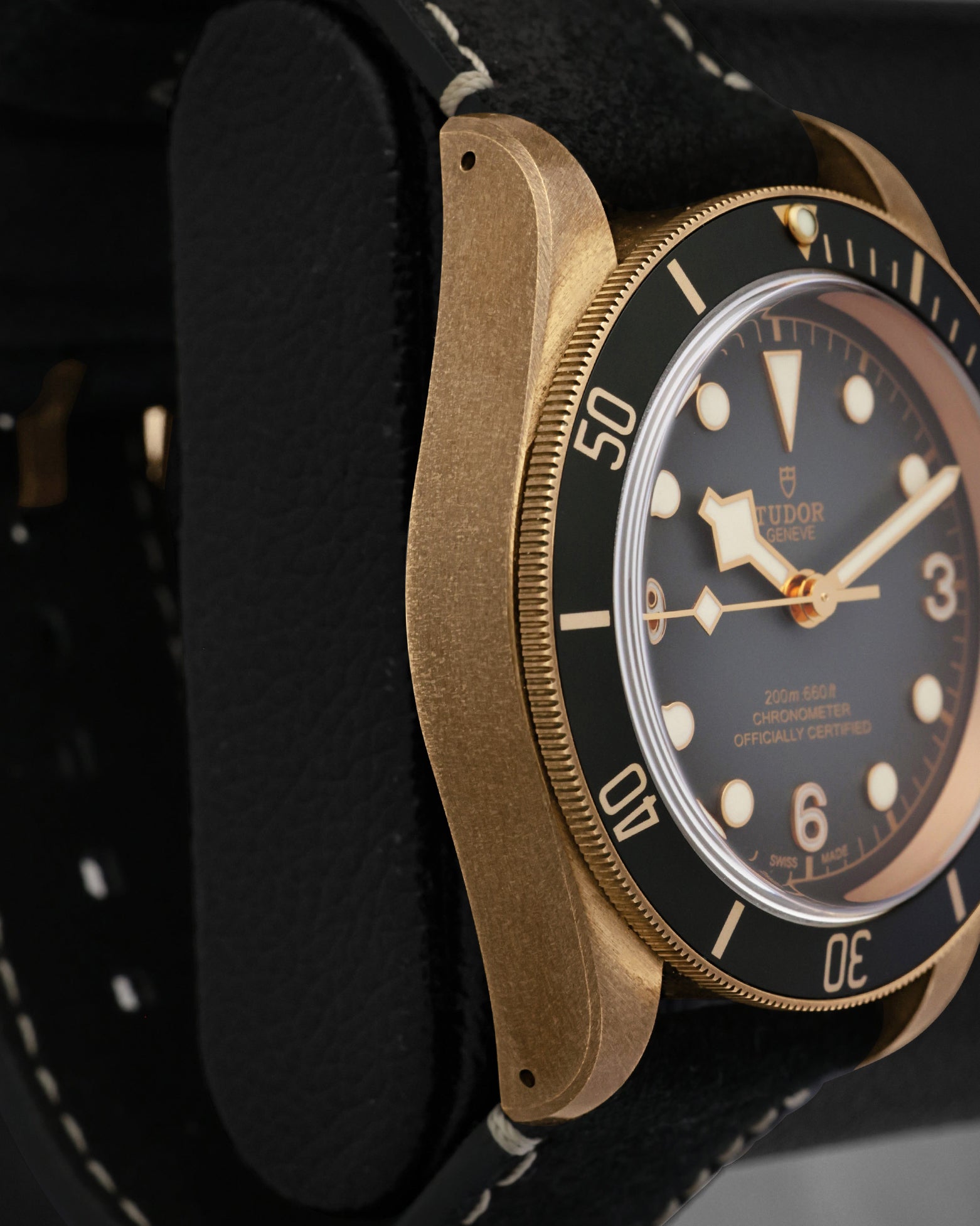 Left side perspective view highlighting the thick domed sapphire crystal, unidirectional matte slate grey aluminum bezel insert, and satin-brushed case lugs