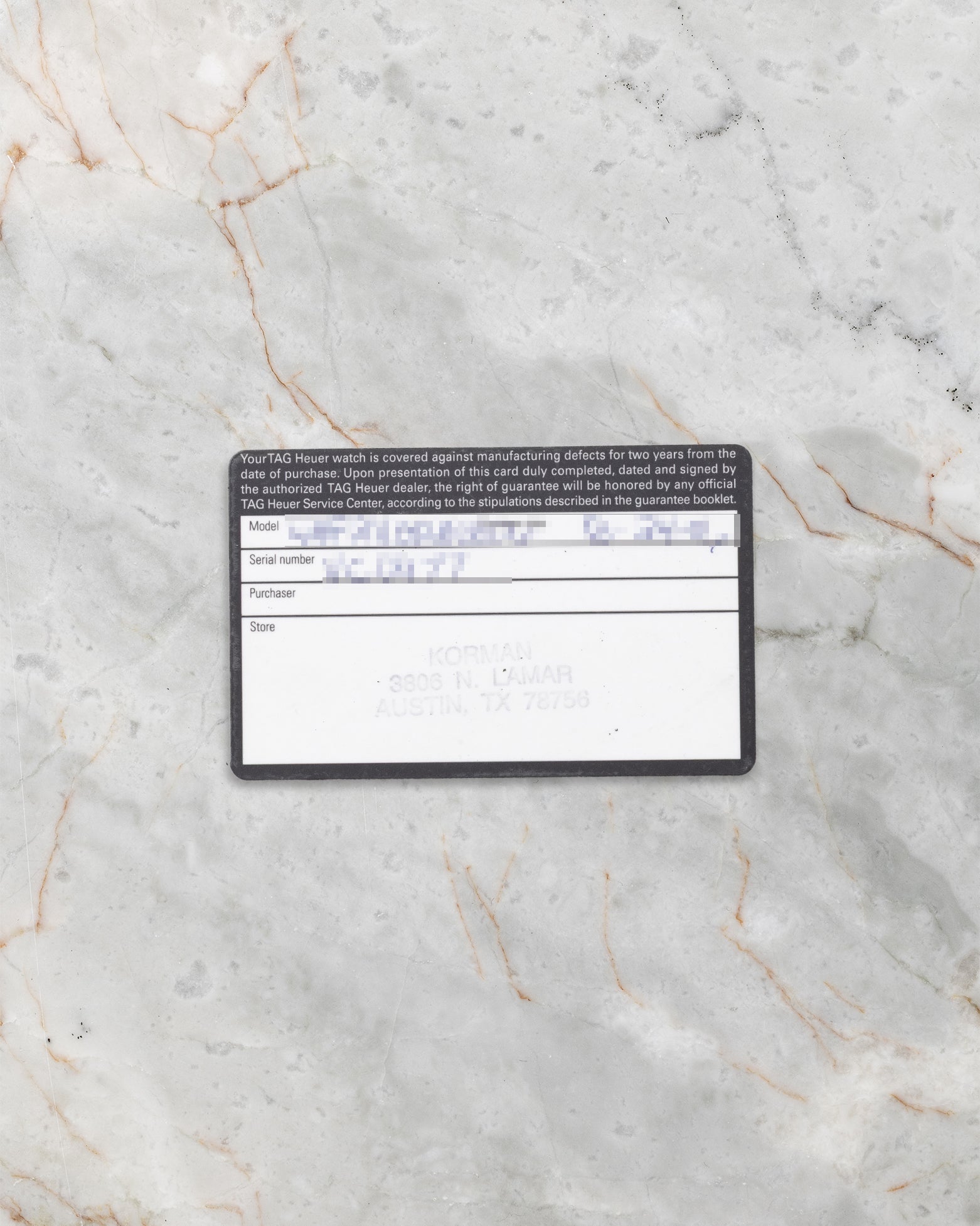 A top-down flat lay view of the original 2006 era printed plastic international guarantee card showing the handwritten model reference and authorized dealer stamps