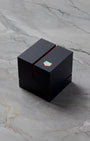 closed modern matte black TAG Heuer luxury watch presentation box featuring a green shield logo accent split on a gray marble background