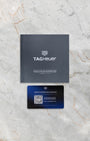 Official dark grey TAG Heuer international guarantee card displayed on marble below its matching brand instruction and service history manual booklet