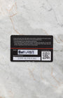 The back of the official black TAG Heuer international warranty card showing QR code and printed serial numbers flat on a marble surface
