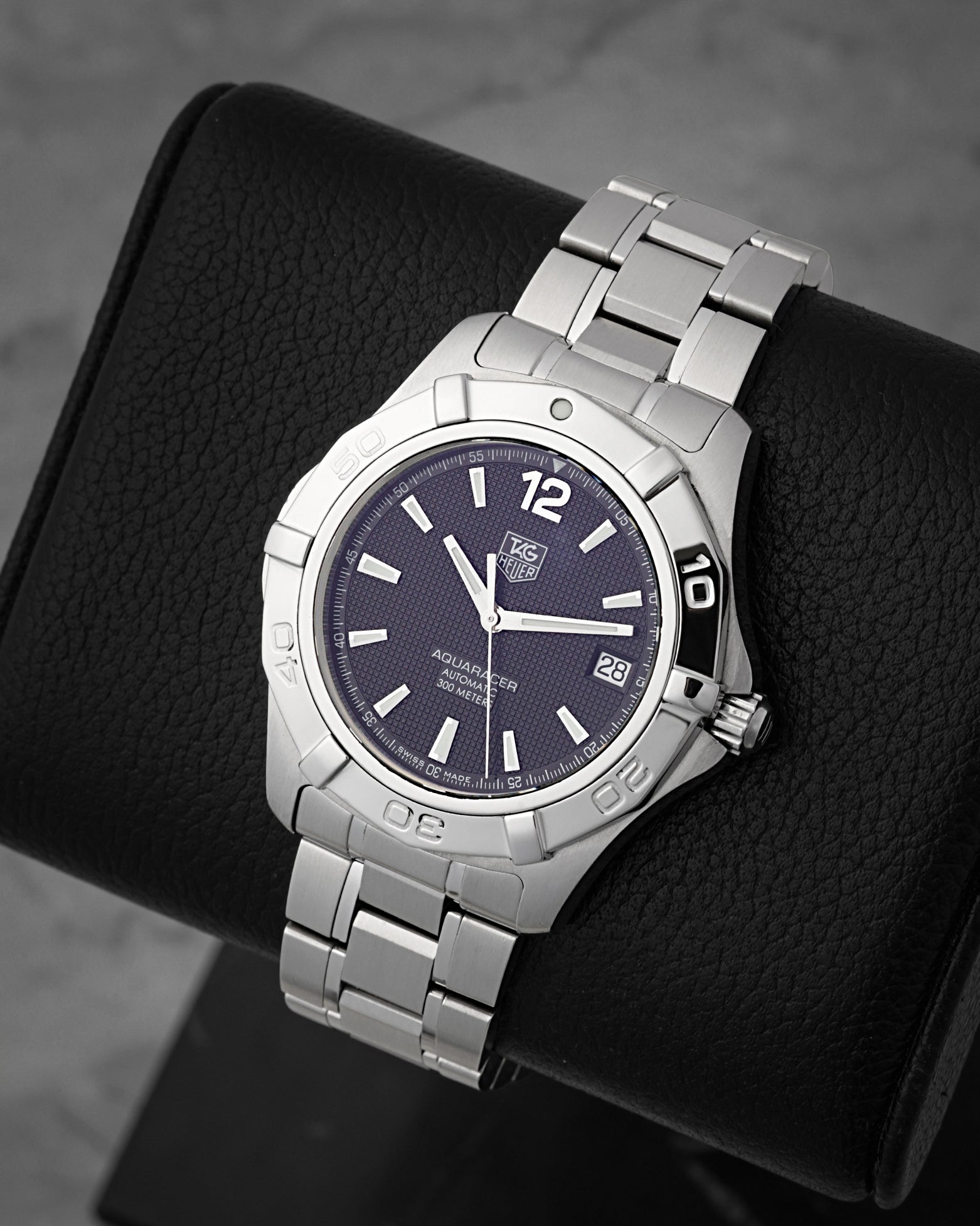 A high-angle three-quarter view of the 38.5mm stainless steel Aquaracer case displaying its rugged rotating diving bezel detailed with raised high-polished rider blocks
