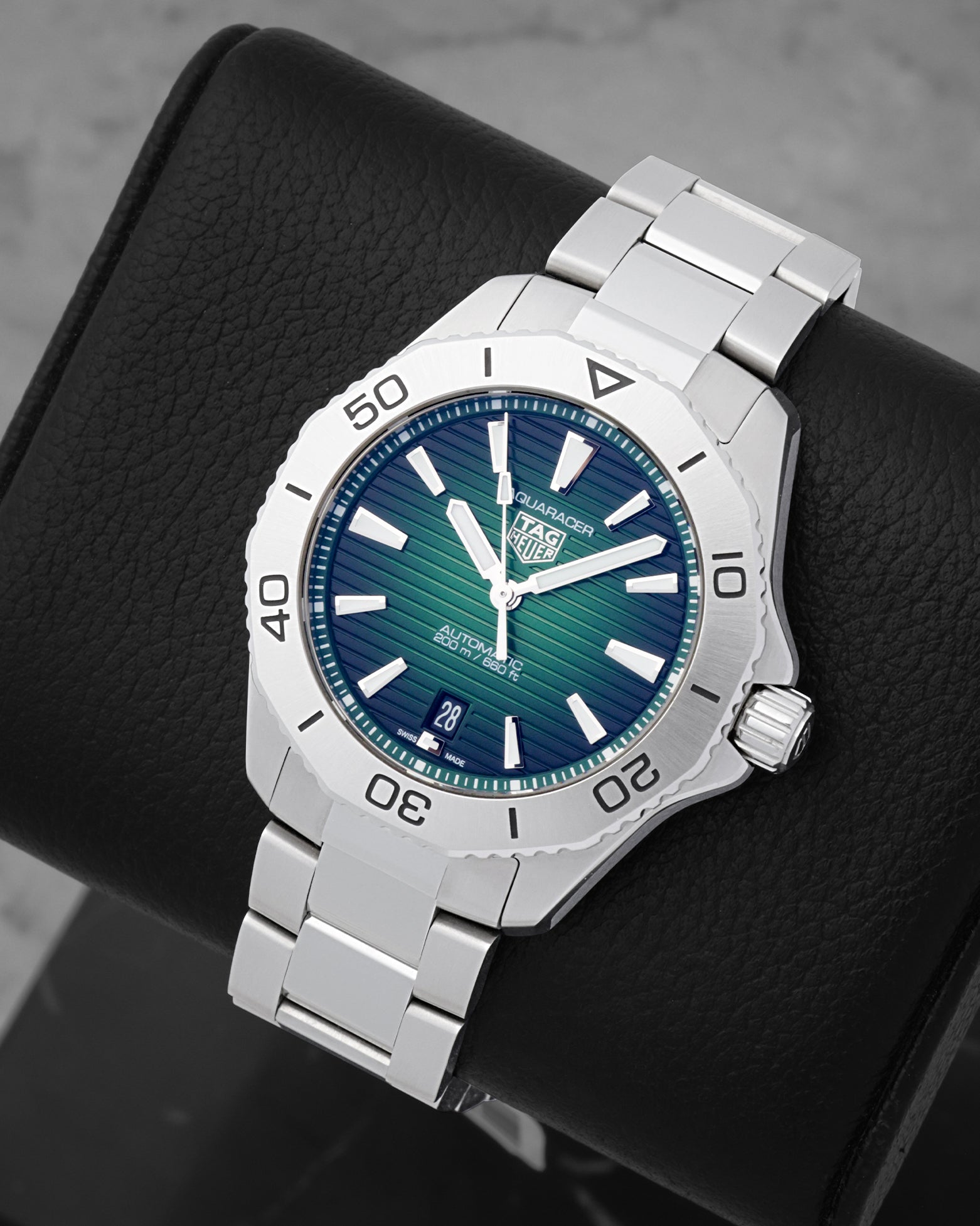 An angled studio profile shot of the 40mm stainless steel TAG Heuer Aquaracer Professional 200 automatic watch on a leather cushion