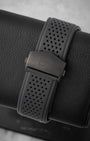rear snapshot focusing on the perforated black rubber racing strap and the dark titanium folding deployment buckle featuring the Heuer shield
