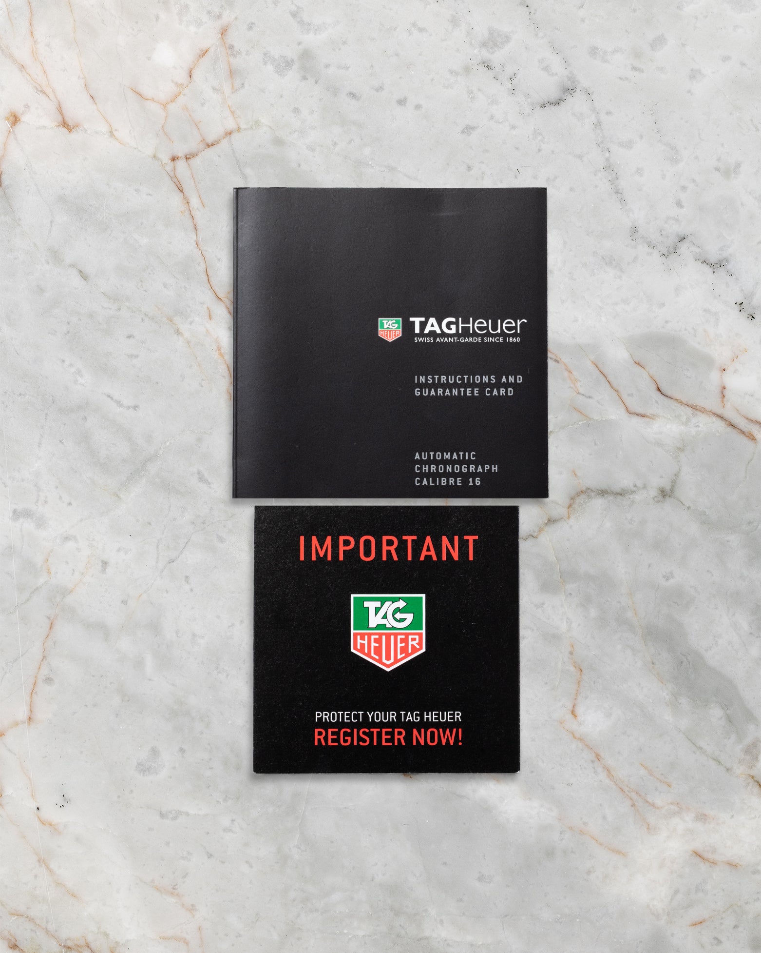 Official TAG Heuer instruction booklet and important service documentation laid out flat on a grey marble surface