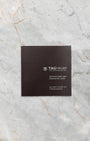 dark textured TAG Heuer official user instruction booklet and service documentation resting flat on a white marble background