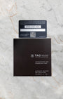 The official TAG Heuer international warranty card and black user manual paperwork laid flat on a marble background
