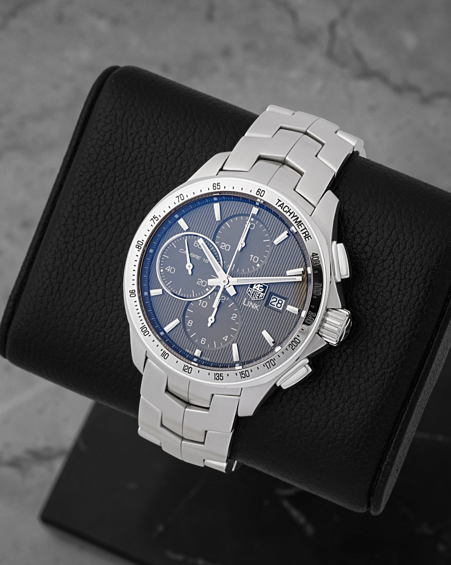 A high-angle three-quarter portrait of the 43mm stainless steel sport chronograph case showcasing its polished steel fixed bezel engraved with a tachymetric scale