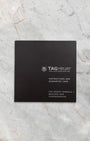 The official black TAG Heuer instructions and guarantee booklet laid flat centered on a white marble background