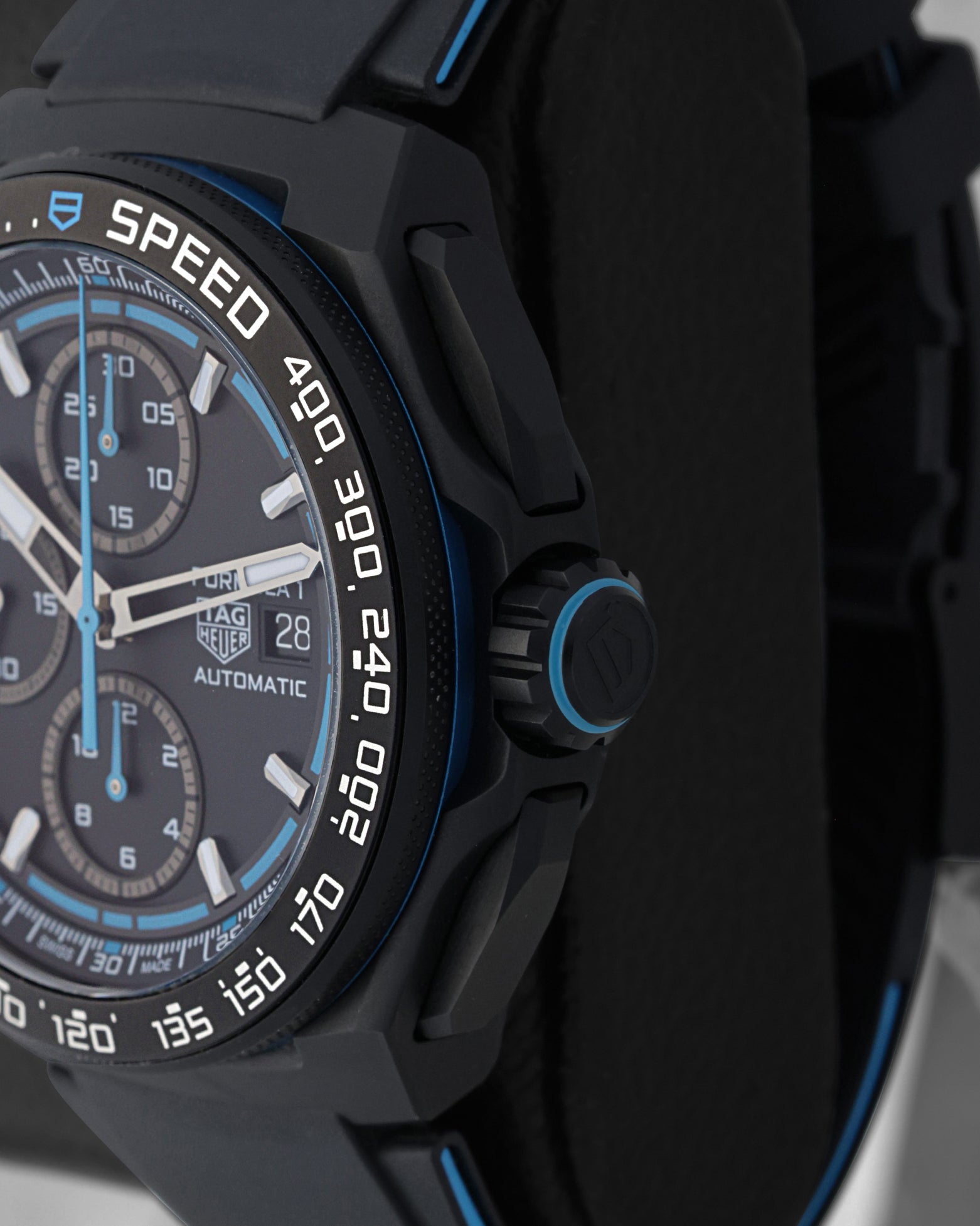 Side profile view of the black sandblasted case showing the racing blue crown ring and integrated sleek chronograph pushers