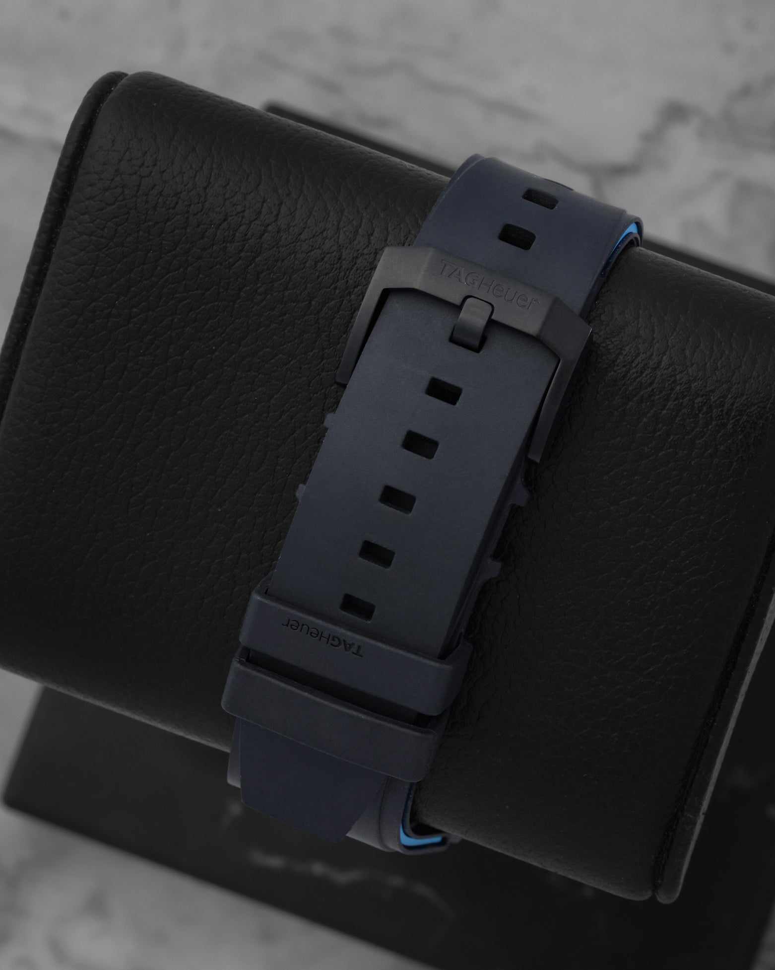 Rear studio view of the textured black rubber strap and matching black DLC coated stainless steel tang buckle closure