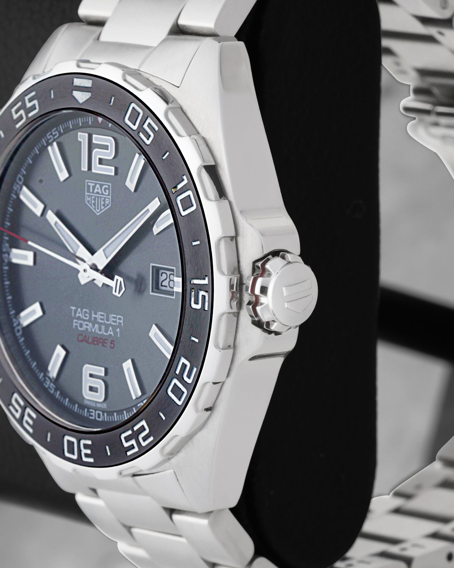 Side profile view of the stainless steel case showing the black ceramic notched bezel, red-accented crown collar, and signed crown