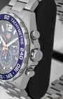 Right side profile view highlighting the screw-down crown, chronograph pushers, and blue aluminum tachymeter bezel on a TAG Heuer Formula 1