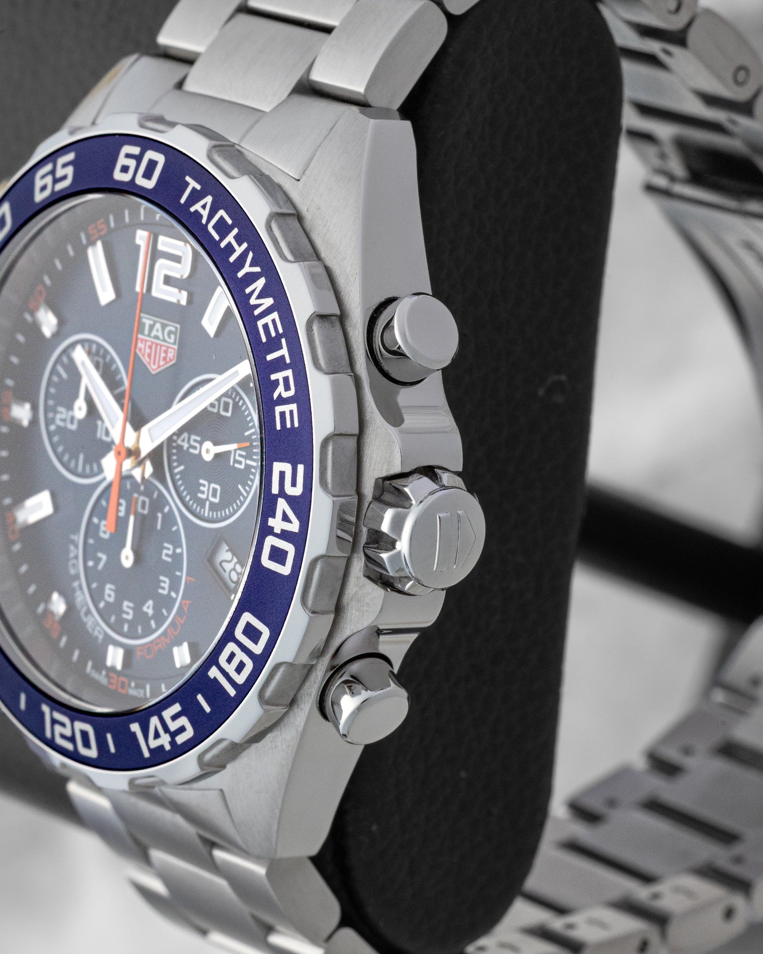 Right side profile view highlighting the screw-down crown, chronograph pushers, and blue aluminum tachymeter bezel on a TAG Heuer Formula 1