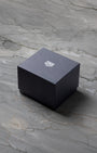 A closed square matte black TAG Heuer luxury watch presentation box sitting centered on a grey marble background