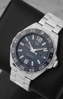 An angled studio profile view of the stainless steel case and link bracelet of a grey TAG Heuer Formula 1 automatic watch