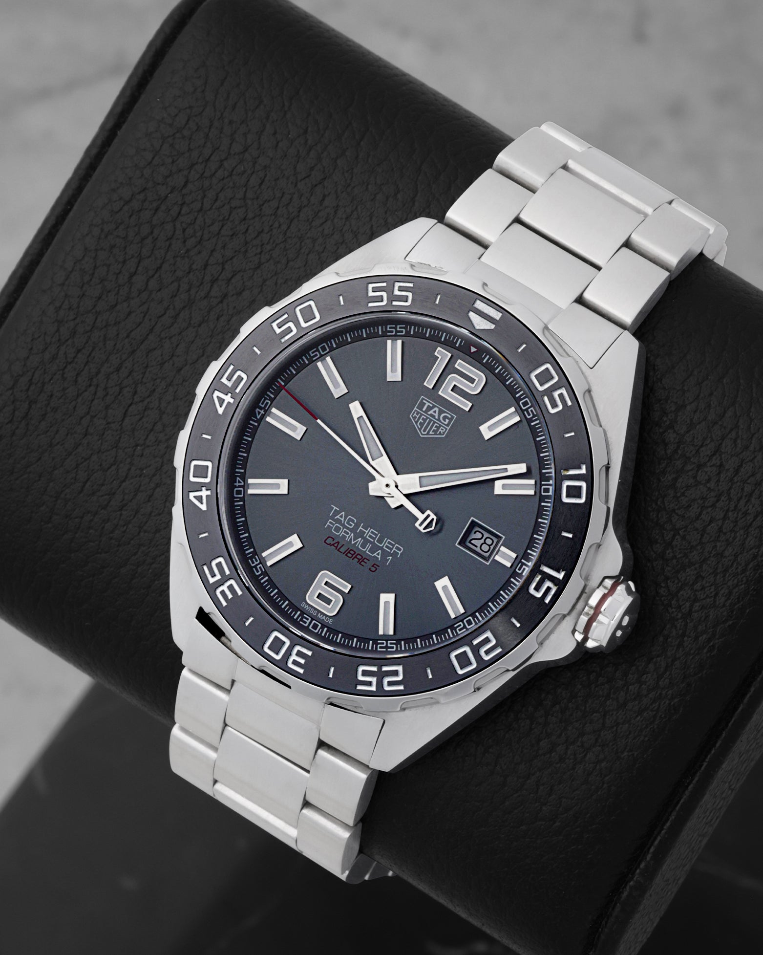An angled studio profile view of the stainless steel case and link bracelet of a grey TAG Heuer Formula 1 automatic watch