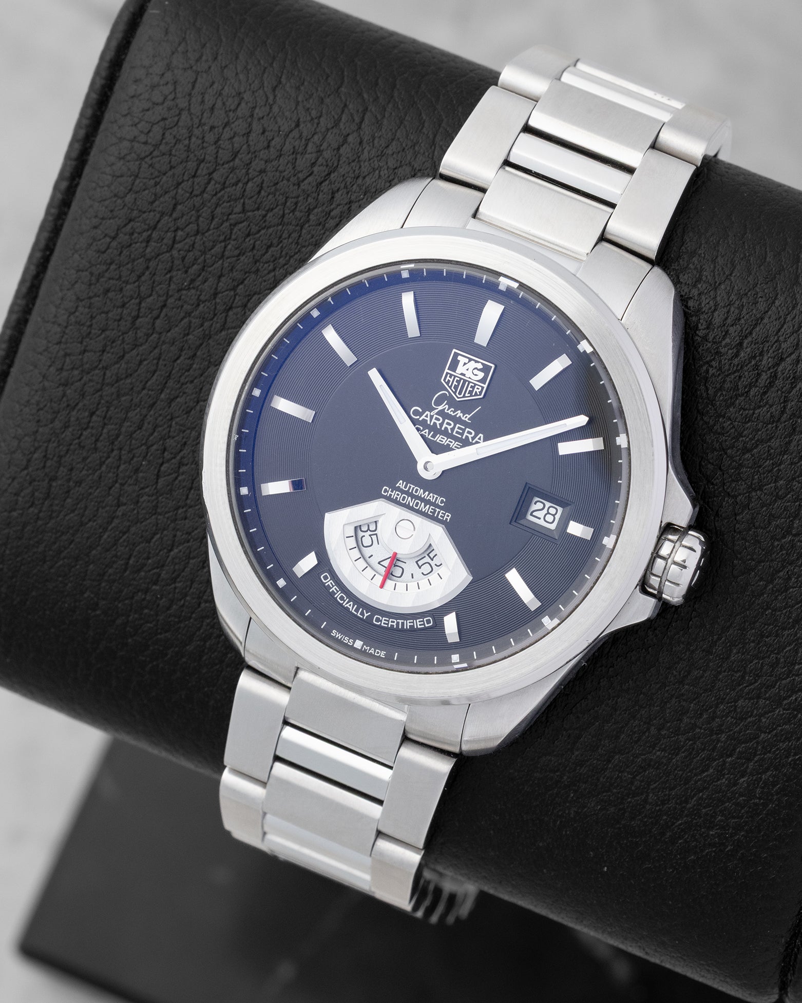 An angled studio view of a stainless steel TAG Heuer Grand Carrera Calibre 6 RS watch resting on a black leather presentation cushion