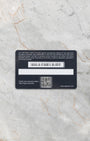 back view of the official TAG Heuer plastic international warranty card showing its magnetic strip flat-laid on light gray marble
