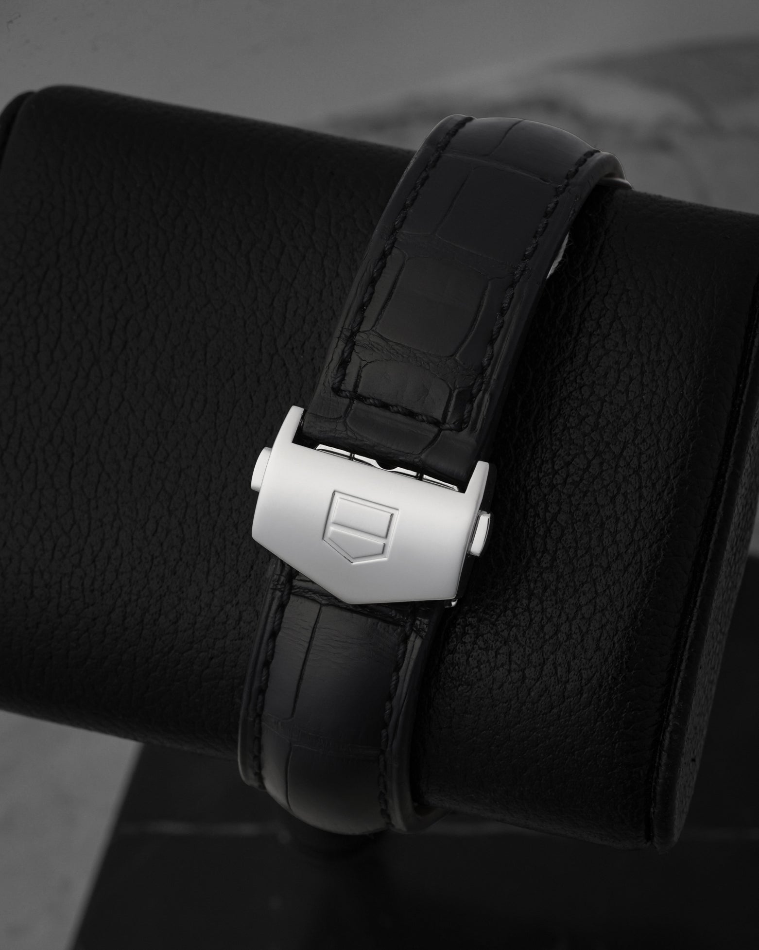 Close-up shot of the satin-finished stainless steel folding single-deployant security buckle detailed with a crisp debossed TAG Heuer shield logo outline