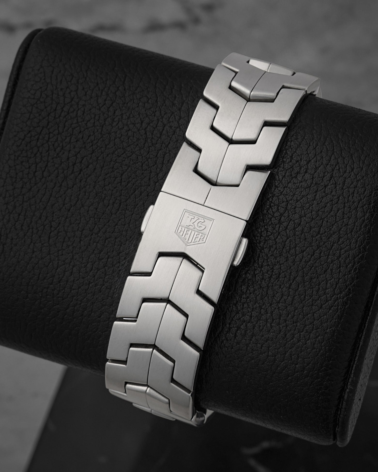 Rear view of the signature interlocking double-S link bracelet focusing on the flush, secure folding deployment buckle detailed with a laser-etched Heuer shield