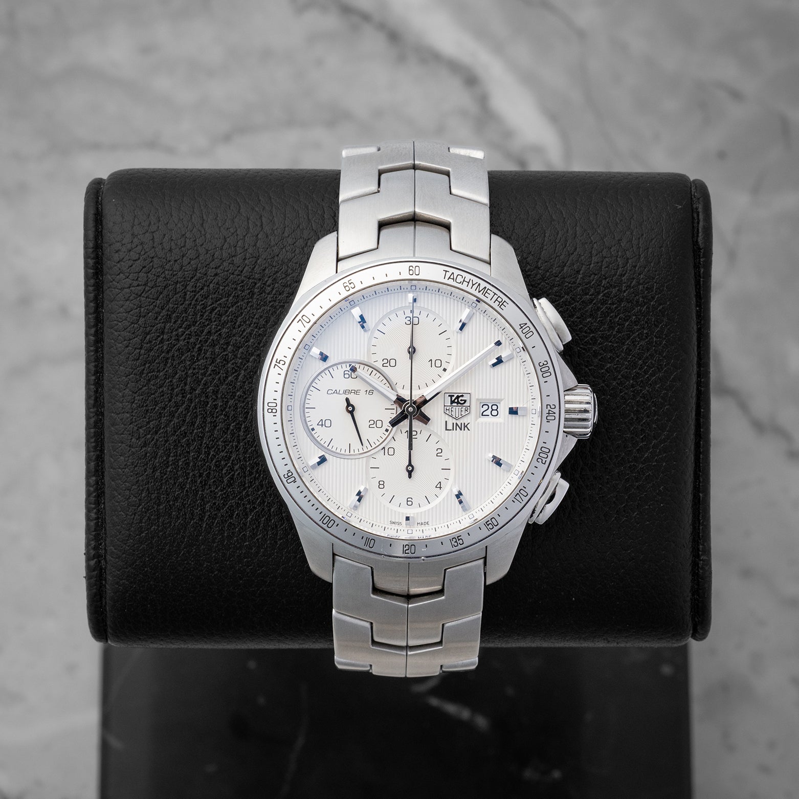 2012 TAG Heuer Link Calibre 16 Automatic Chronograph CAT2011.BA0952 with a silver dial on a black studio display stand