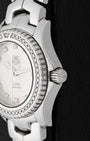A close-up right profile view focusing on the polished screw-down crown with the embossed TAG Heuer shield logo and the precise edge of the hand-set diamond bezel