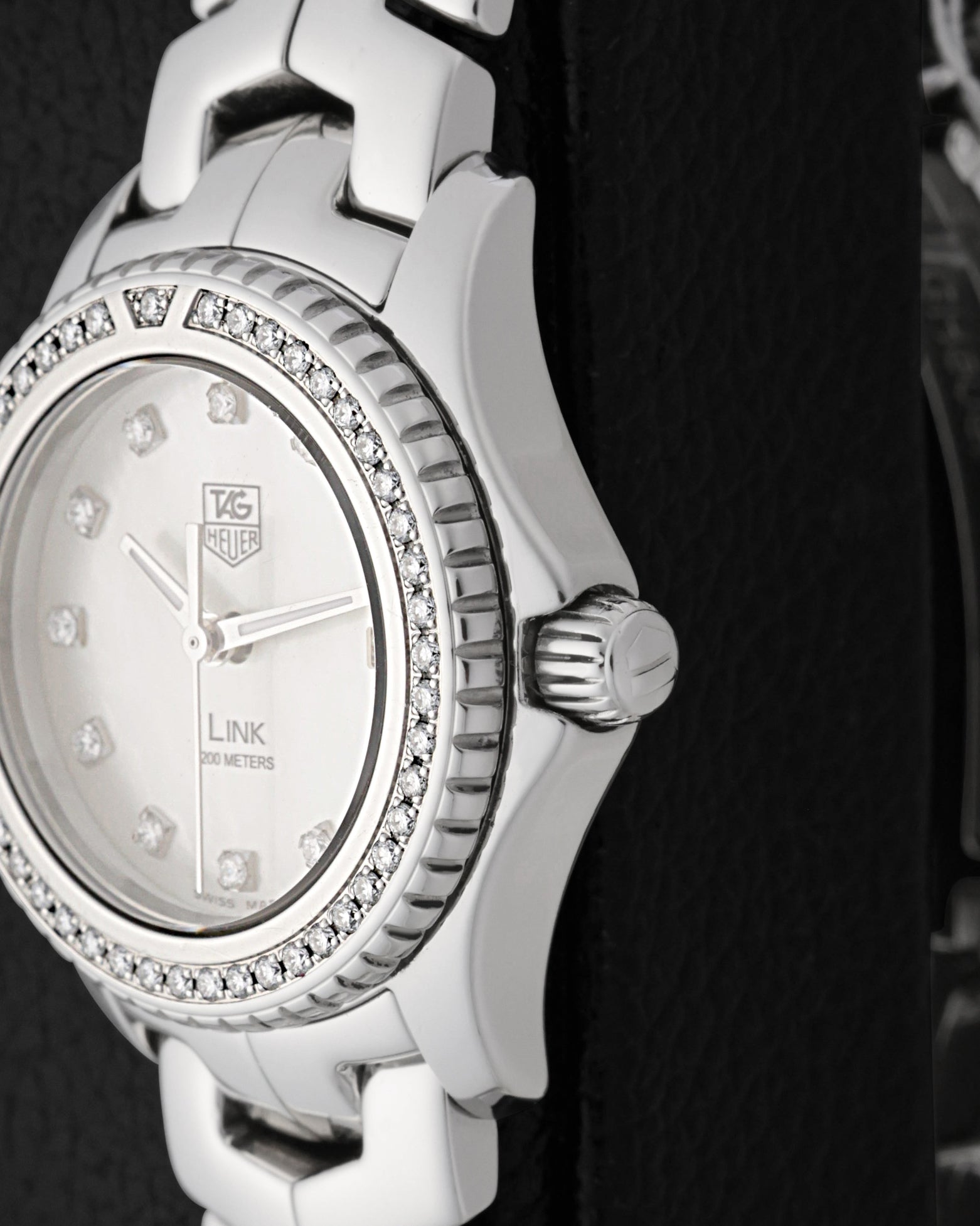 A close-up right profile view focusing on the polished screw-down crown with the embossed TAG Heuer shield logo and the precise edge of the hand-set diamond bezel
