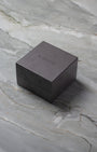 A closed brown TAG Heuer luxury watch presentation box sitting on a textured grey marble surface.
