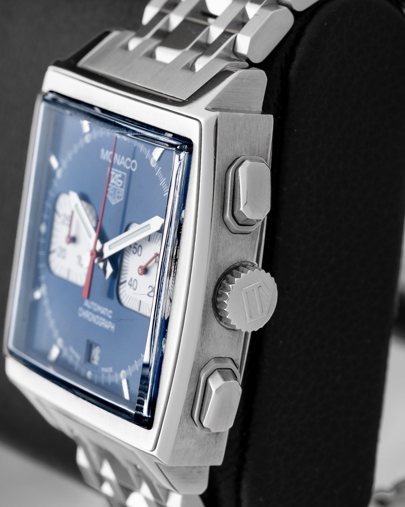 Side profile showing the square stainless steel case, signed winding crown, and rectangular chronograph pushers on a TAG Heuer Monaco CW2113