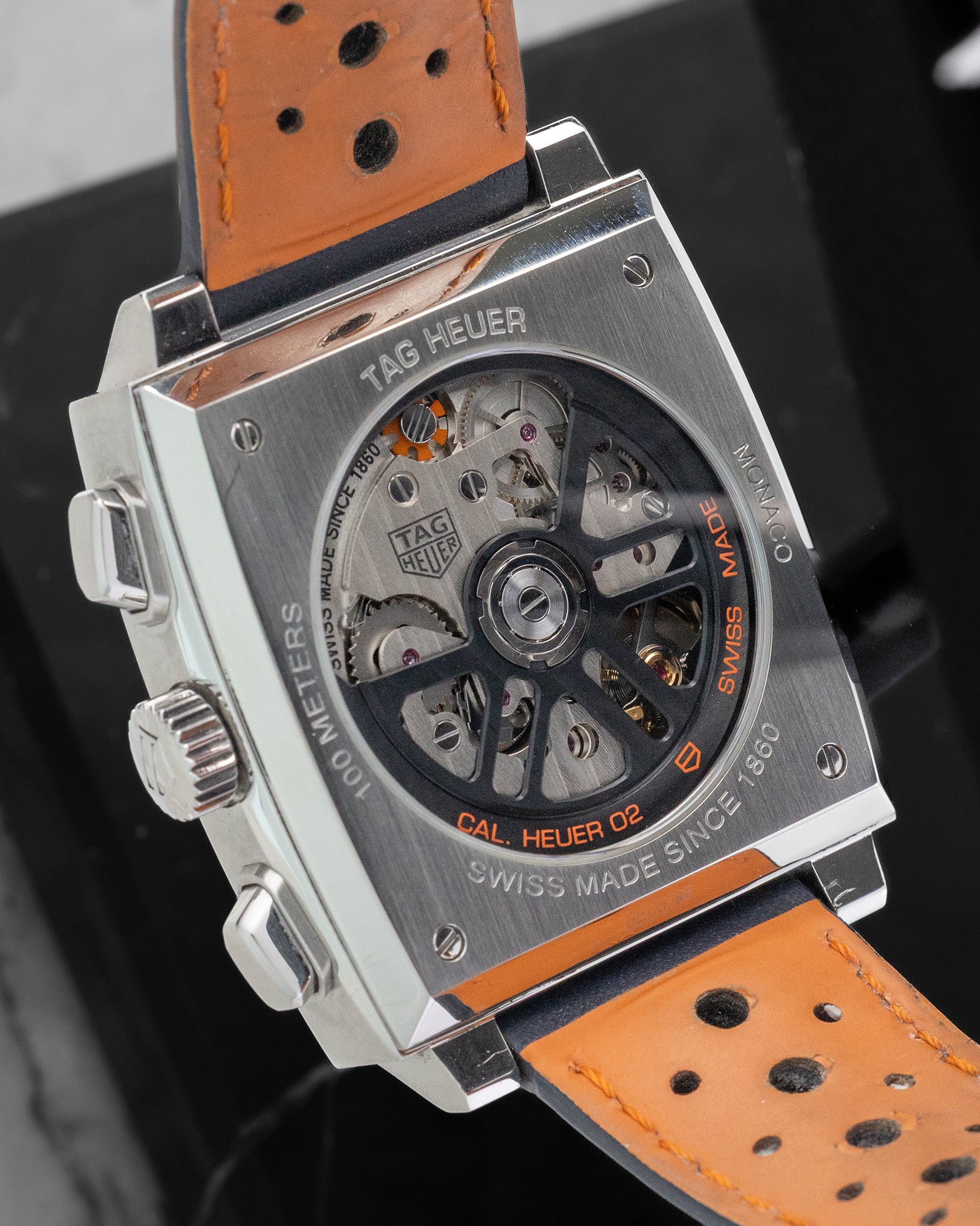 Sapphire crystal exhibition caseback displaying the in-house Heuer 02 automatic chronograph movement and orange lining of the perforated strap.