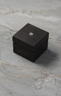 A high-angle three-quarter shot of the official vintage-style square black pebble-grain watch storage box featuring the colored brand shield crest on top