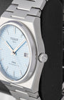 Close-up right side profile of the angular brushed stainless steel Tissot PRX case featuring the T-engraved crown