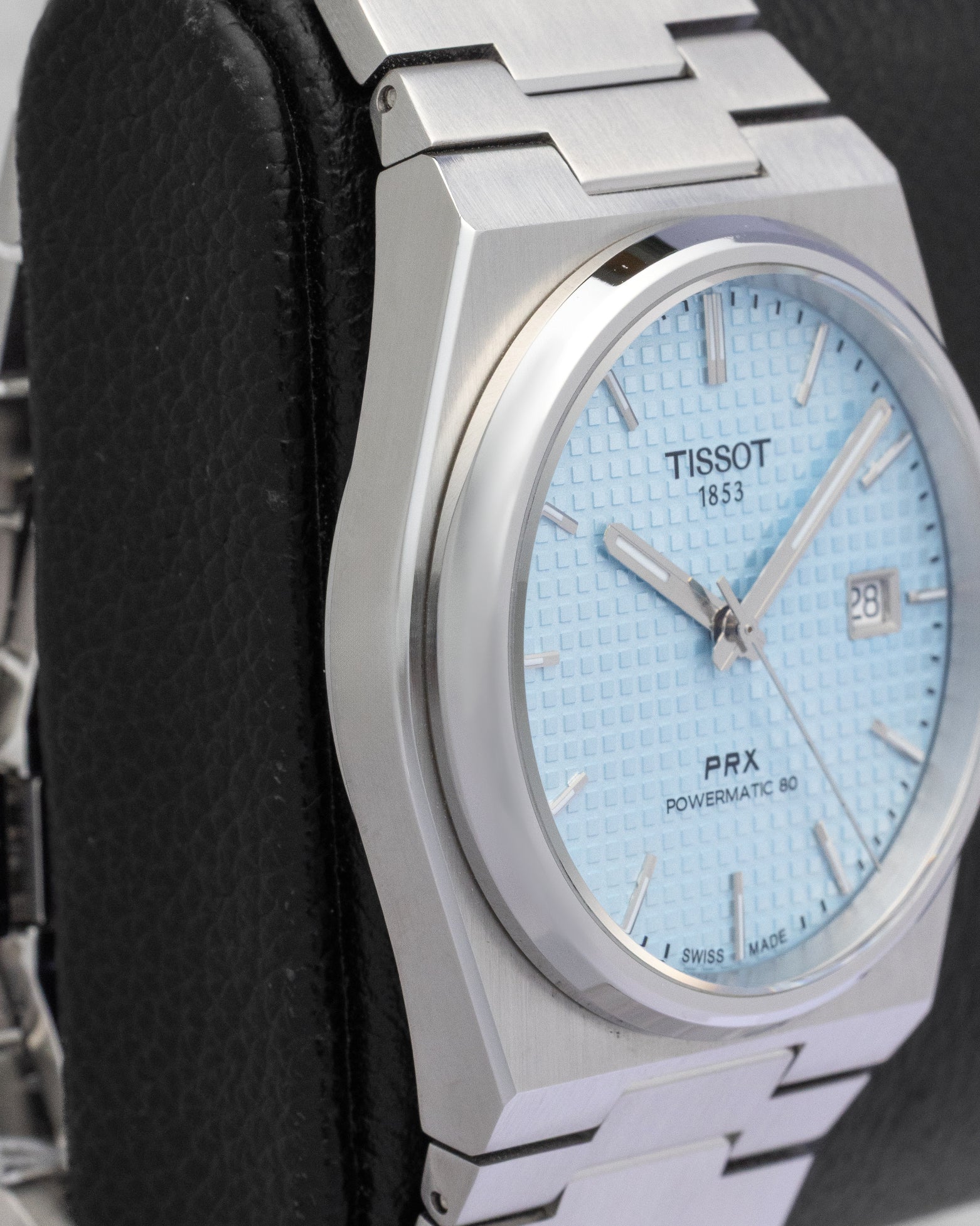 Left side view of the slim integrated case and smooth bezel profile on a 40mm Tissot PRX steel watch