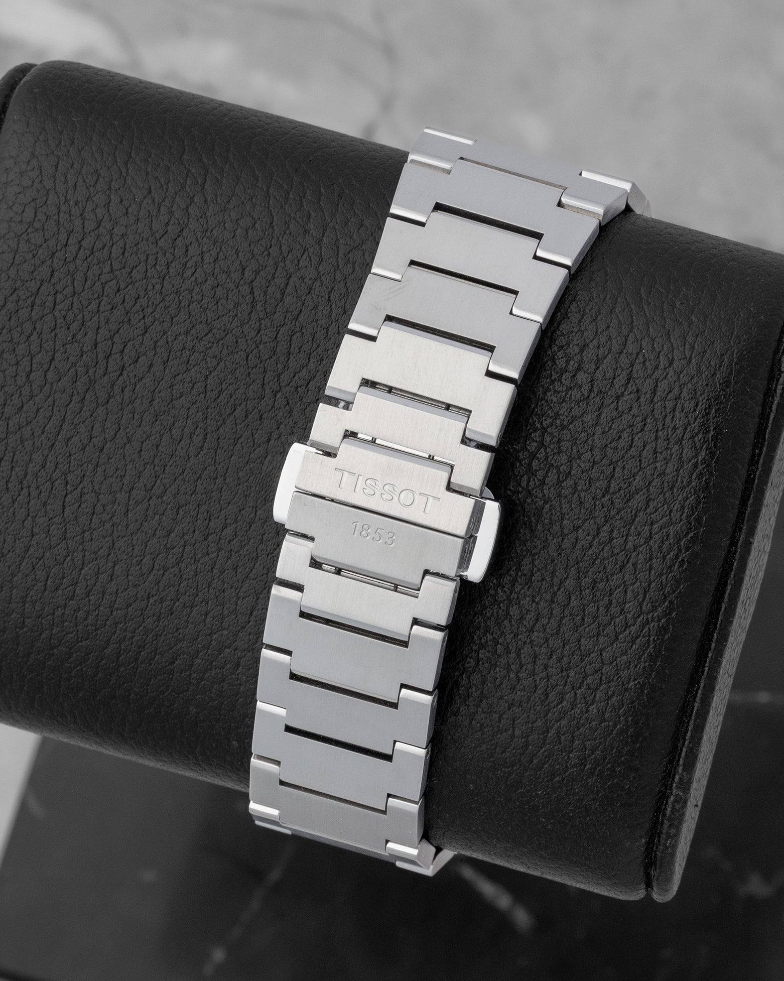The seamless integrated stainless steel link bracelet and engraved butterfly clasp on a Tissot PRX watch