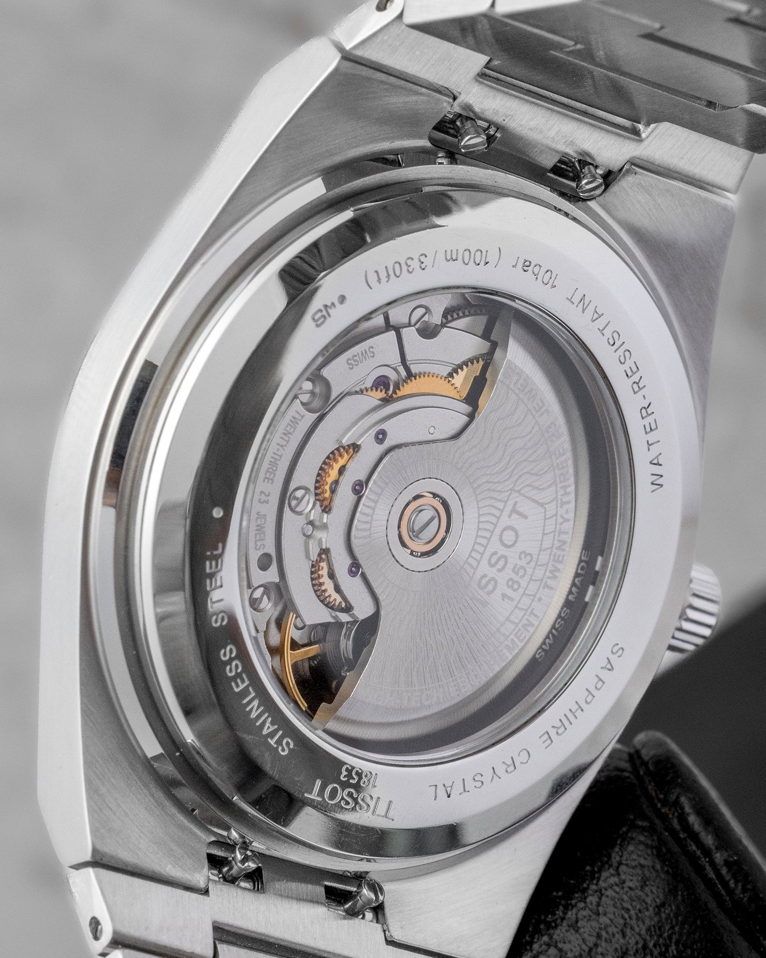 The open sapphire crystal exhibition caseback of a Tissot PRX watch revealing the automatic movement rotor