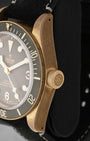 Side profile focus on the natural patinated bronze case finish and the prominent screw-down winding crown engraved with the Tudor rose