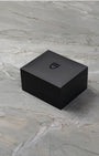 angled overview of the closed textured black Tudor luxury watch presentation box sitting on a stone studio surface