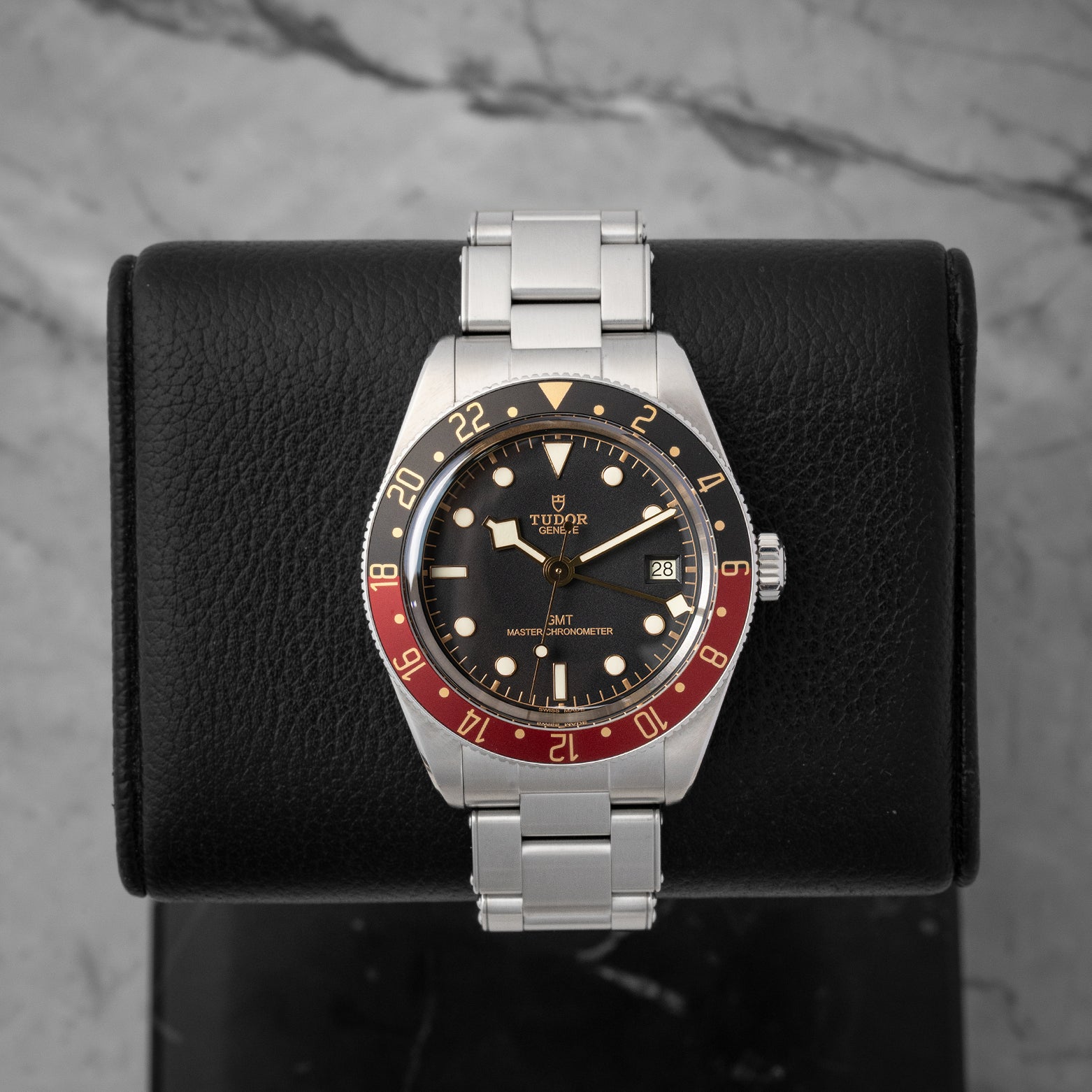 studio front portrait of the 39mm Tudor Black Bay 58 GMT 7939G watch featuring its black and burgundy bezel on a leather stand