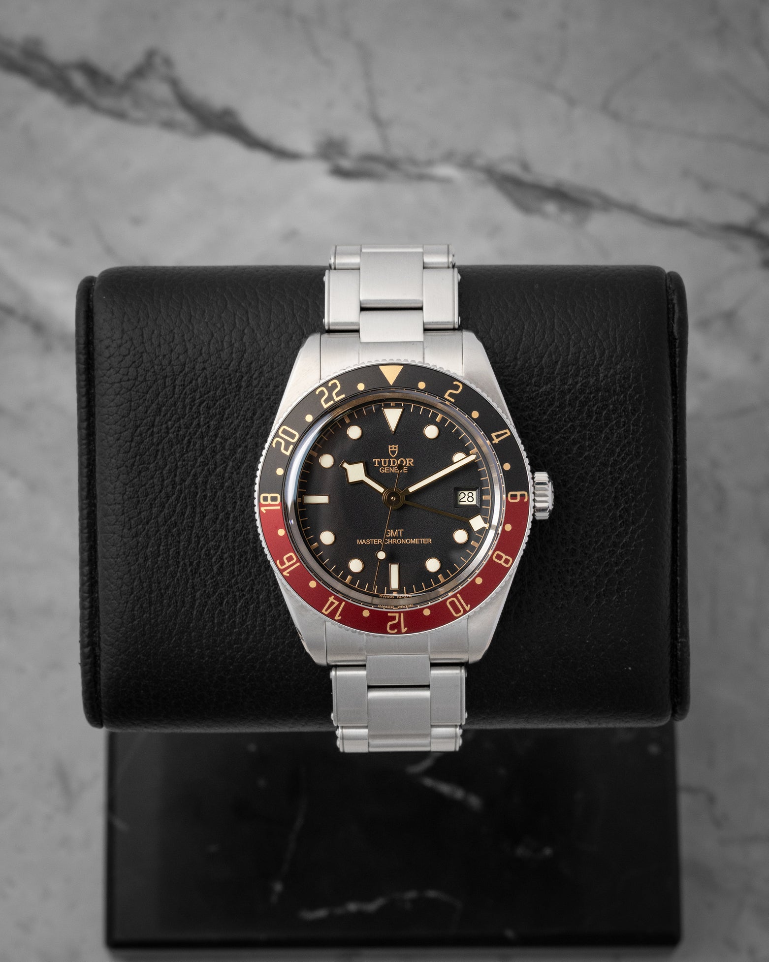 studio front portrait of the 39mm Tudor Black Bay 58 GMT 7939G watch featuring its black and burgundy bezel on a leather stand